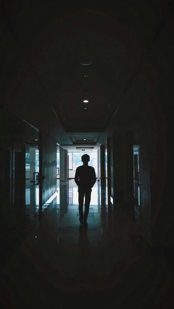 A silhouette of a man walking down a dimly lit hallway, creating a mysterious ambiance.