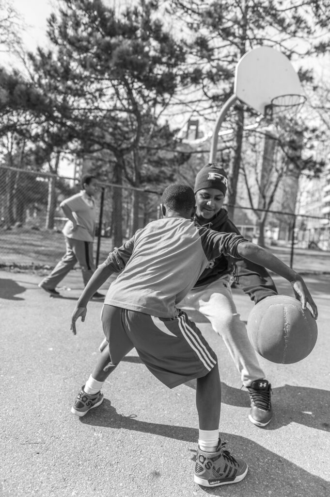 Two boys playing intense basketball on an outdoor court, showcasing teamwork and athleticism.