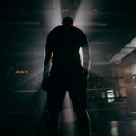 Silhouette of a boxer in a gym, illuminated by dramatic beams of sunlight, creating a powerful visual impact.