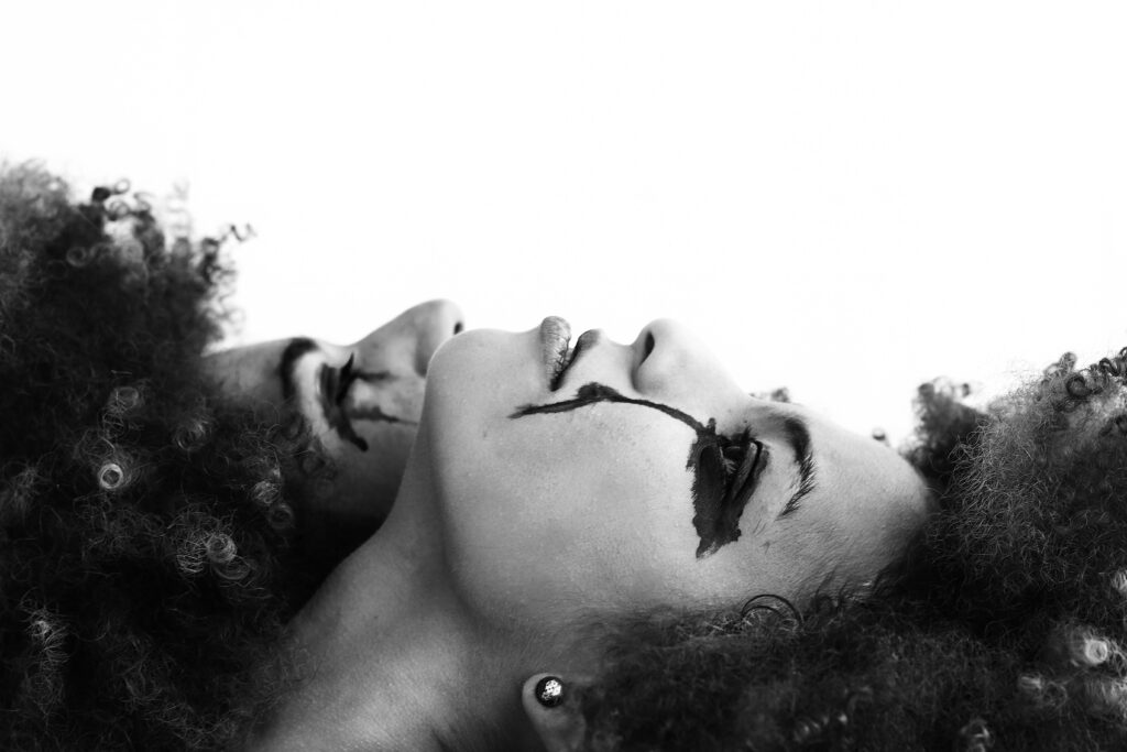 Black and white artistic photo of a woman with expressionist makeup, conveying emotion.