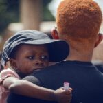 A comforting moment between a man and child, showcasing emotional support in Nigeria.