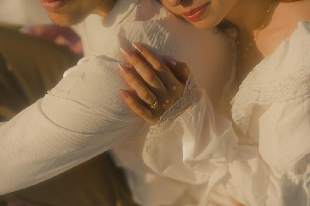 Close-up of an engaged couple embracing, showcasing vintage-inspired style and engagement ring.