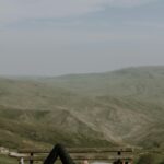 Man reclining on a bench amidst scenic hills for leisure and relaxation.