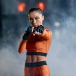 A woman in activewear delivering a punch in a hazy gym scene, demonstrating fitness and strength.