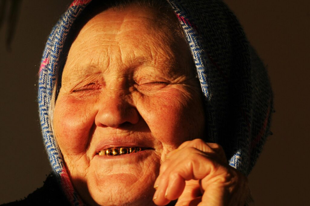 Close-up of a senior woman's joyful smile and expressive face in warm light.