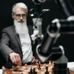 An older man engages in a strategic chess game with a robotic arm, illustrating the blend of tradition and technology.
