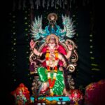 Intricately adorned Ganesha statue on a throne, surrounded by vibrant decorations. Perfect for religious and cultural themes.