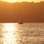 Sailboat gliding on Lake Vättern during a vibrant sunset in Jönköping, Sweden.