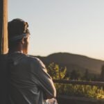 A man in solitude watches the serene sunset over the mountains, embracing tranquility.