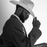 Profile of a stylish man in a cowboy hat and suit, in elegant black and white.