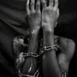 Striking black and white image of a person in chains, evoking emotion and depth.